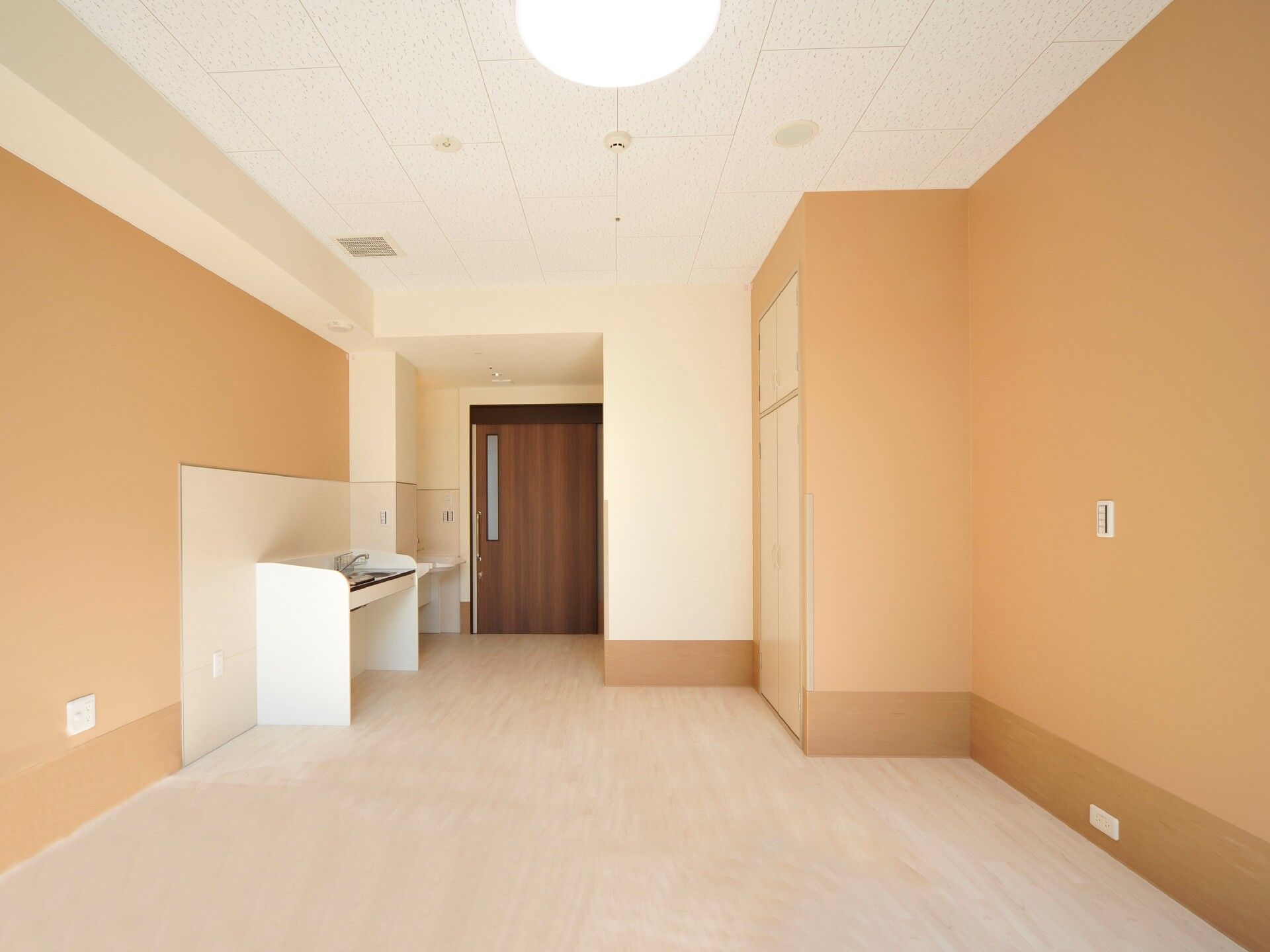 スライド式のドアが設置されたフローリングの部屋にはキッチンや洗面所が設置され、いずれも車いす対応のデザイン。