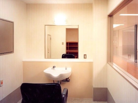 小さな洗面台と理美容専用の椅子が置いてある施設内の理美容室の写真