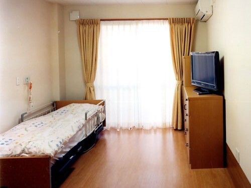 テレビやタンスが置いてある施設内の居室。小さなワンルームタイプの部屋