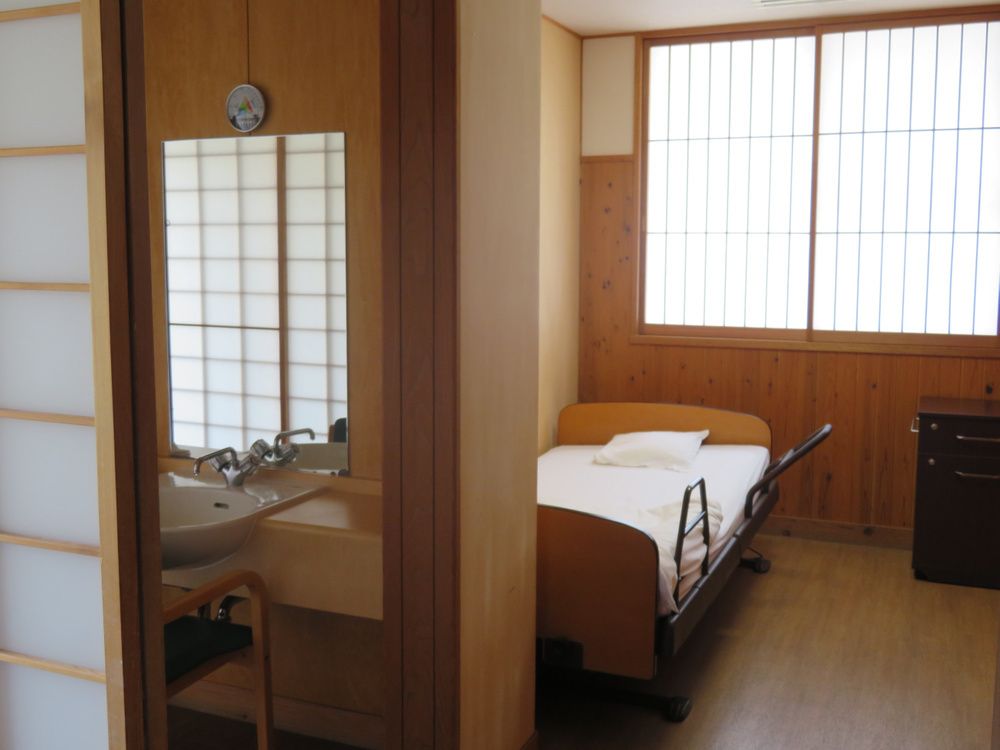 介護用ベッドや洗面所が付いた居室。窓には障子が付いている。