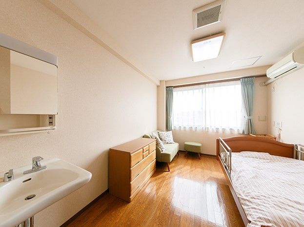 洗面所が付いた居室には収納やベッドソファが置かれ、大きな窓があり明るい雰囲気。