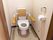 トイレは間口が広く、車椅子を使う方も出入りしやすく造られている。安全のため、背もたれ付きの手すりが便器に設置されている。