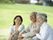 日当たりのいい芝生の上でおしゃべりをしている高齢の夫婦と若い女性スタッフ。