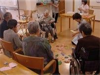 高齢者が集まってレクリエーションに興じている様子。施設内の活動の一場面