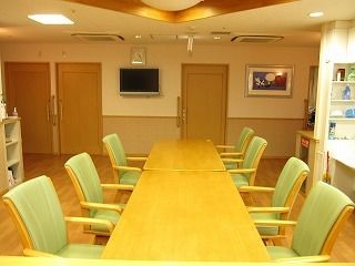 緑色の椅子を並べた長いテーブルで食事をいただく。団欒スペースでもあり、入居者様同士の交流を持つことができる。
