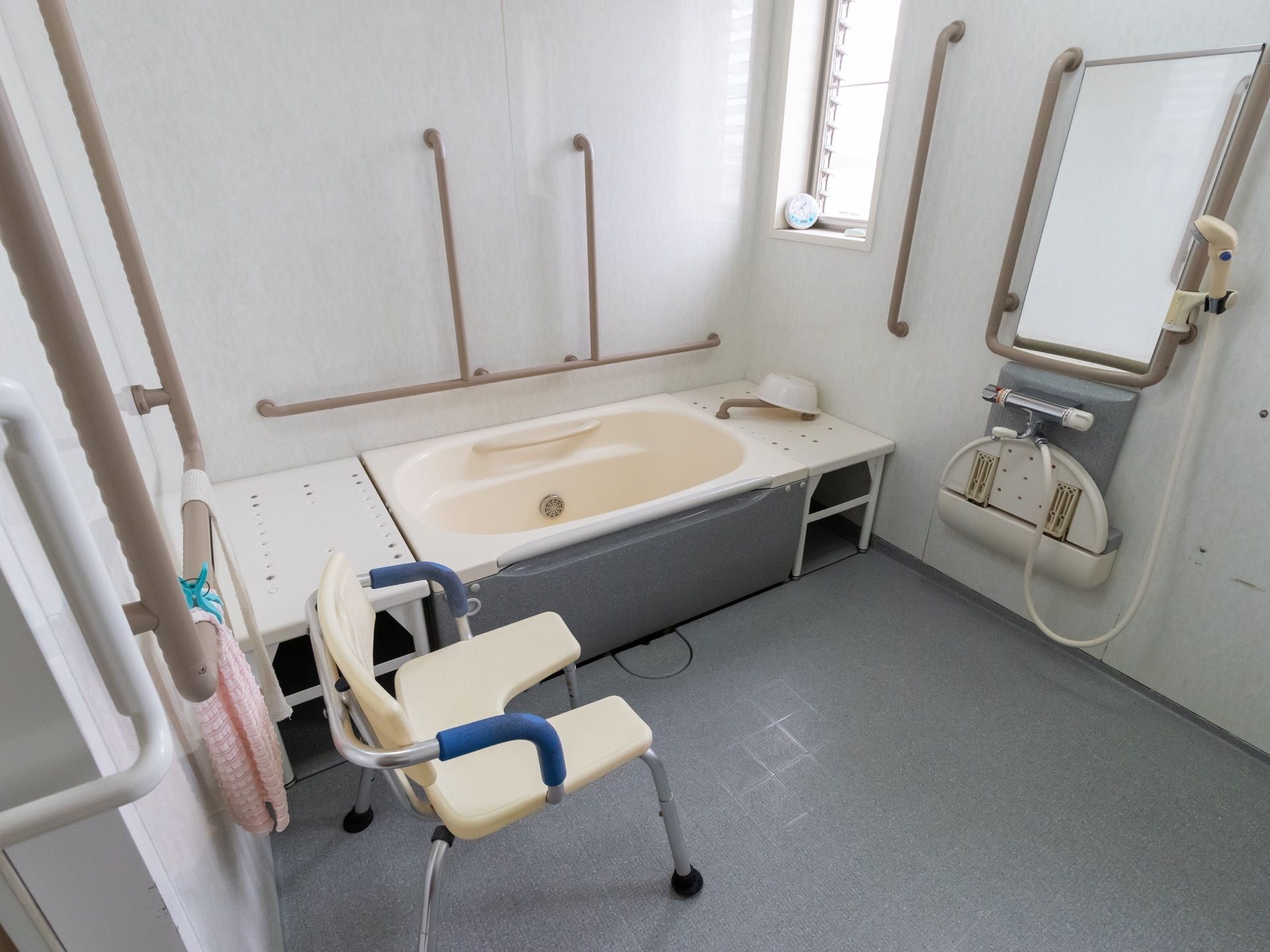 入居者様が安全にシャワーを浴びていただけるよう、シャワーチェアを設置している。浴室内には手すりが多く取り付けられている。