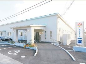 平屋建ての老人向け施設の外観。バリアフリーで駐車スペースが用意してある