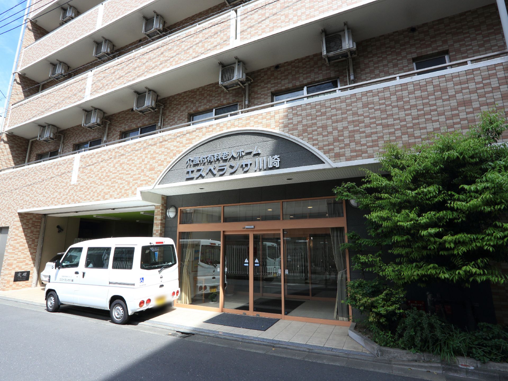 施設入口の上の部分に施設の種類と名前が表示されている。初めて来た人も分かりやすい。入口は自動ドアで、駐車スペースもある。