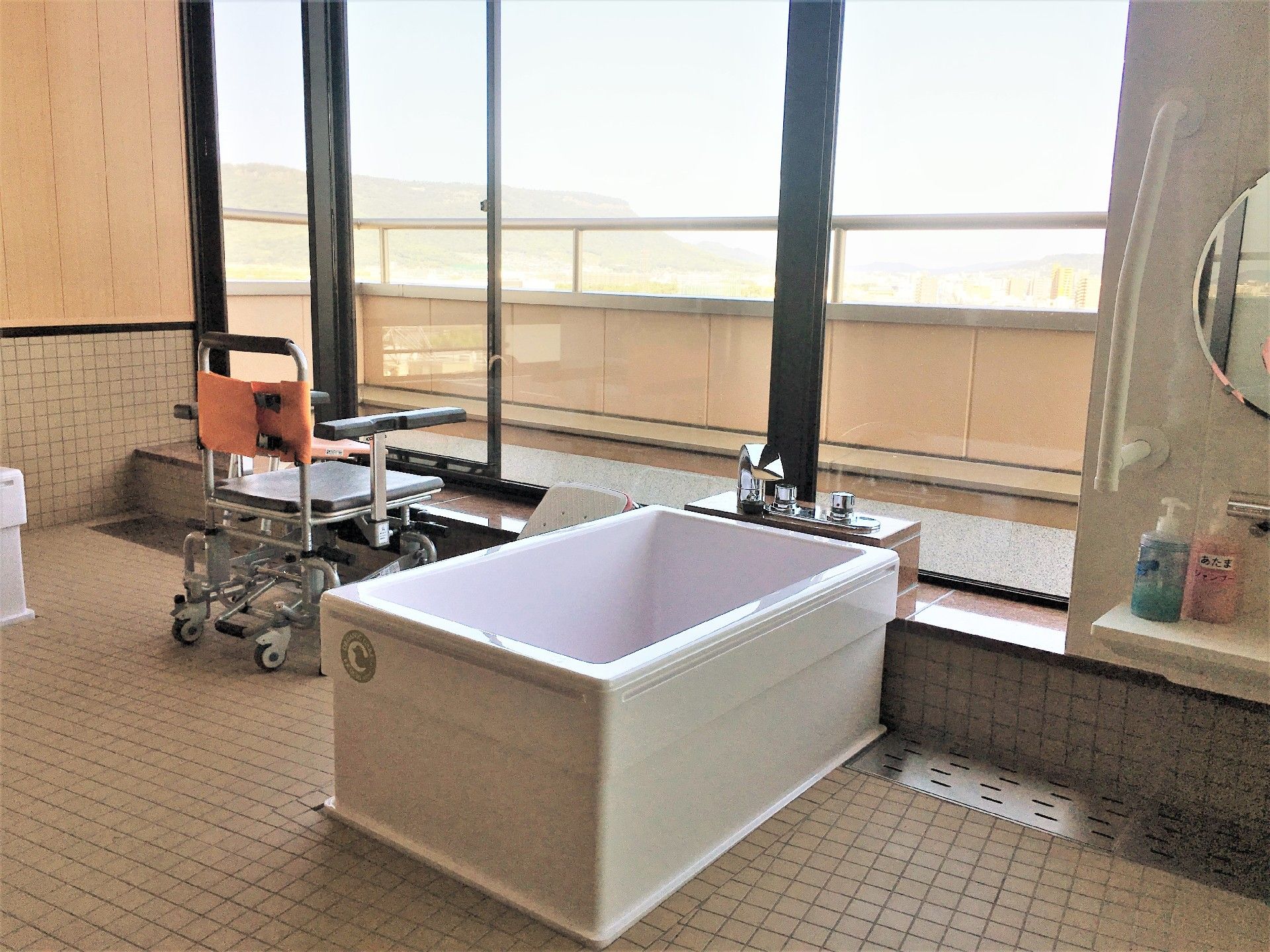 一人用の浴槽が設置された浴室。シャワーや浴室用車いすもあり、大きな窓がついている。