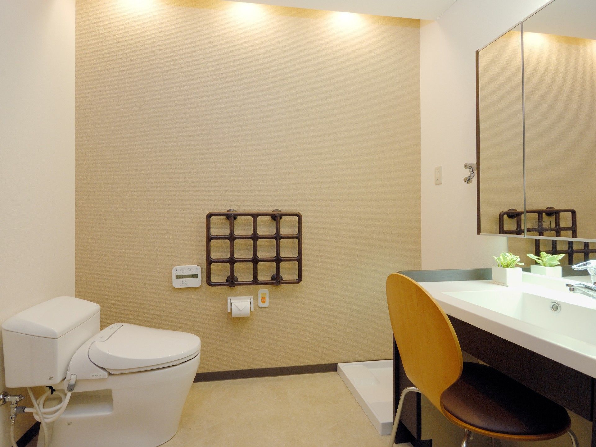 05大きな鏡が付いた広い洗面所があり、左の壁には格子状の手すりが付き、トイレもある。