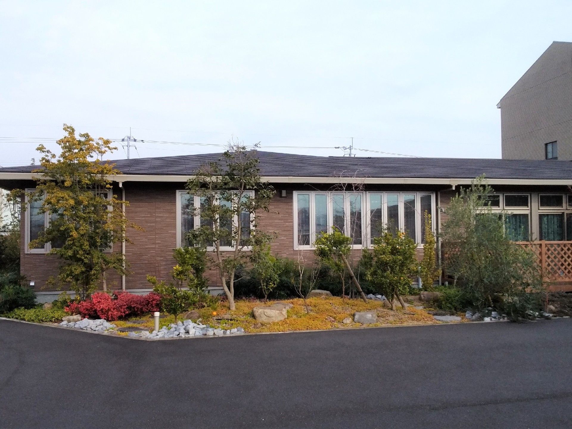 ブラウンでまとめられた落ち着いた雰囲気の外観。建物周辺には木が植えられている。