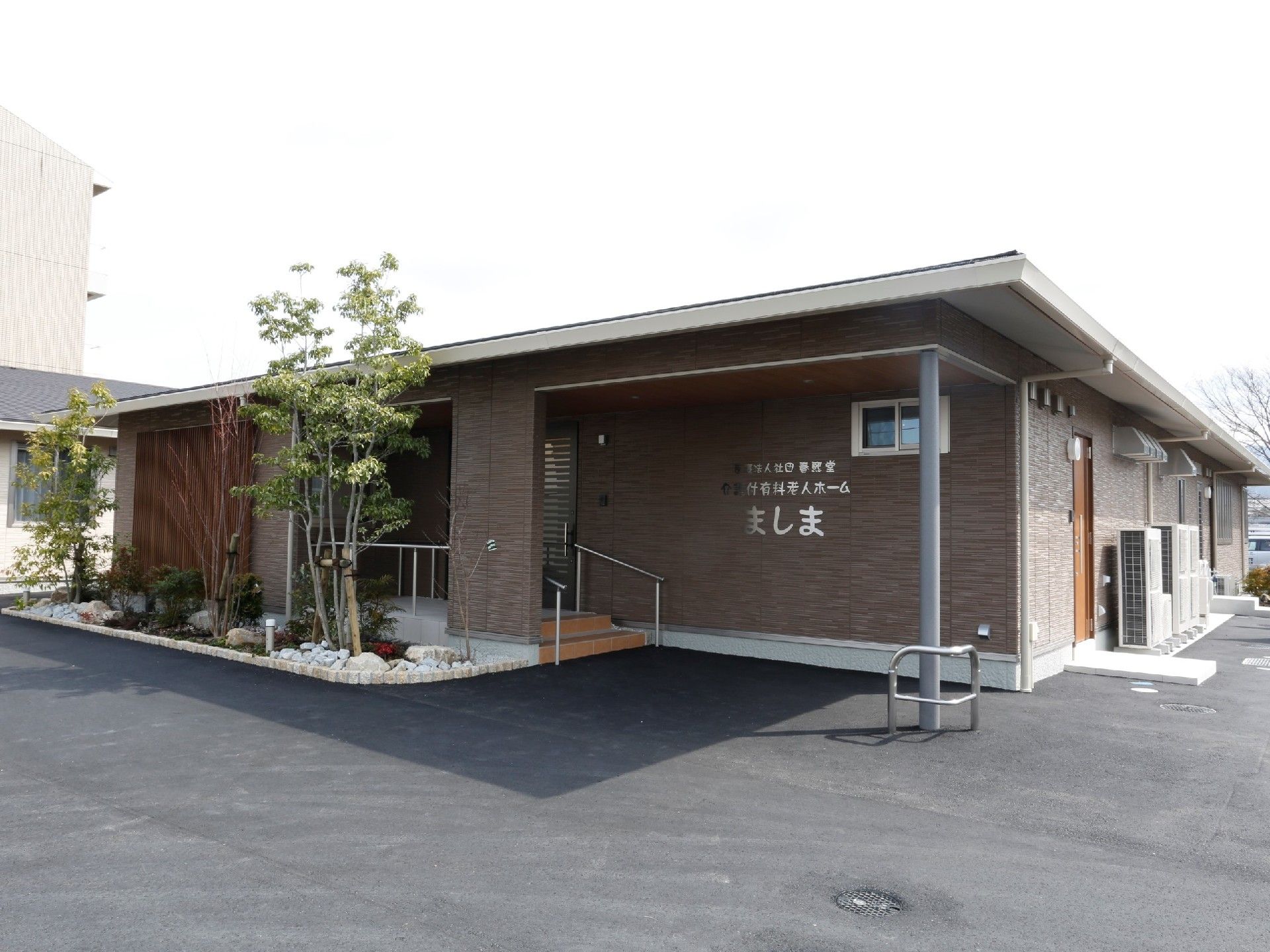 平屋建ての建物。広い駐車スペースもあり、ホームの看板が真正面にあり、周辺には季節の花も植えられている。