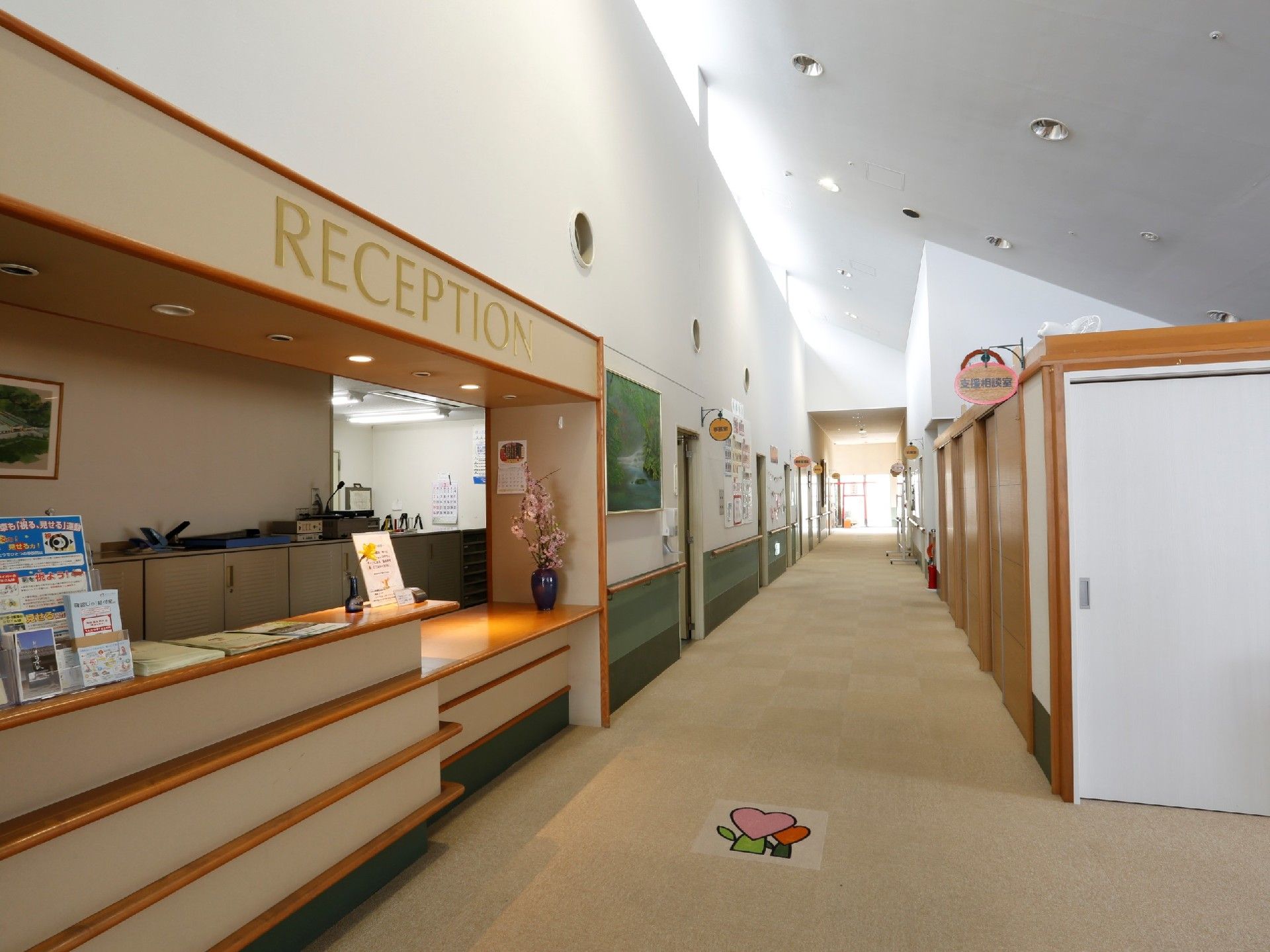 「RECEPTION」と書かれた受付。廊下にはカーペットが敷かれ、天井が高く開放感がある。