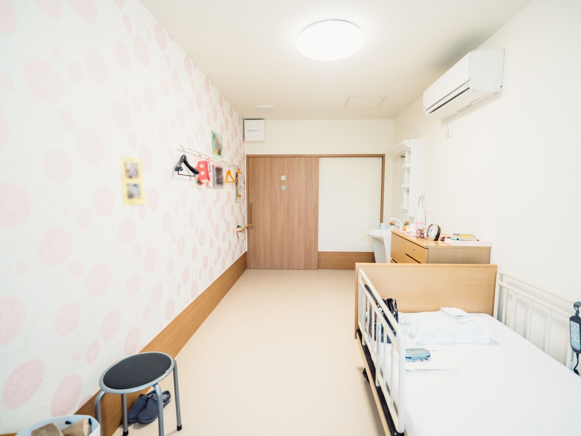 白を基調とした室内に、ベッドと収納ダンスが置かれている。壁にはハンガーがかけられるようになっており、空間が有効活用されている。