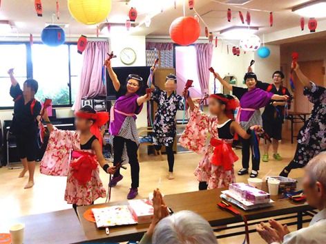 館内の天井には提灯が飾られ、赤い花柄の衣装と鉢巻をした子供たちと紫と黒の衣装を着た大人がよさこいを踊っている。