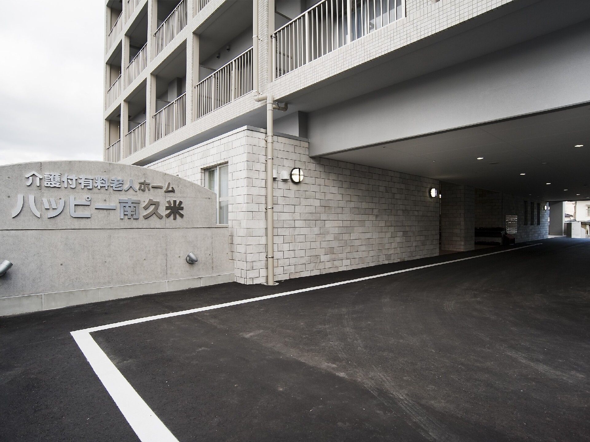 建物の１階部分は駐車場となっていて、駐車場の入り口には館銘板が建っている。