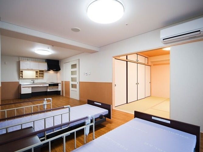 ベッドが２台設置され、畳敷きの和室やキッチンも付いた広い部屋。エアコンも付いている。