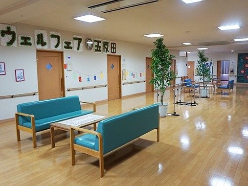 居室のドアが並び、ドアを開けるとテーブルセットや平行棒、ソファの応接セットがある共有スペースがある。
