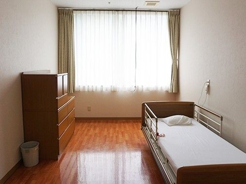 寝具付きのベッドやタンス、ゴミ箱などが設置されたフローリングの部屋。