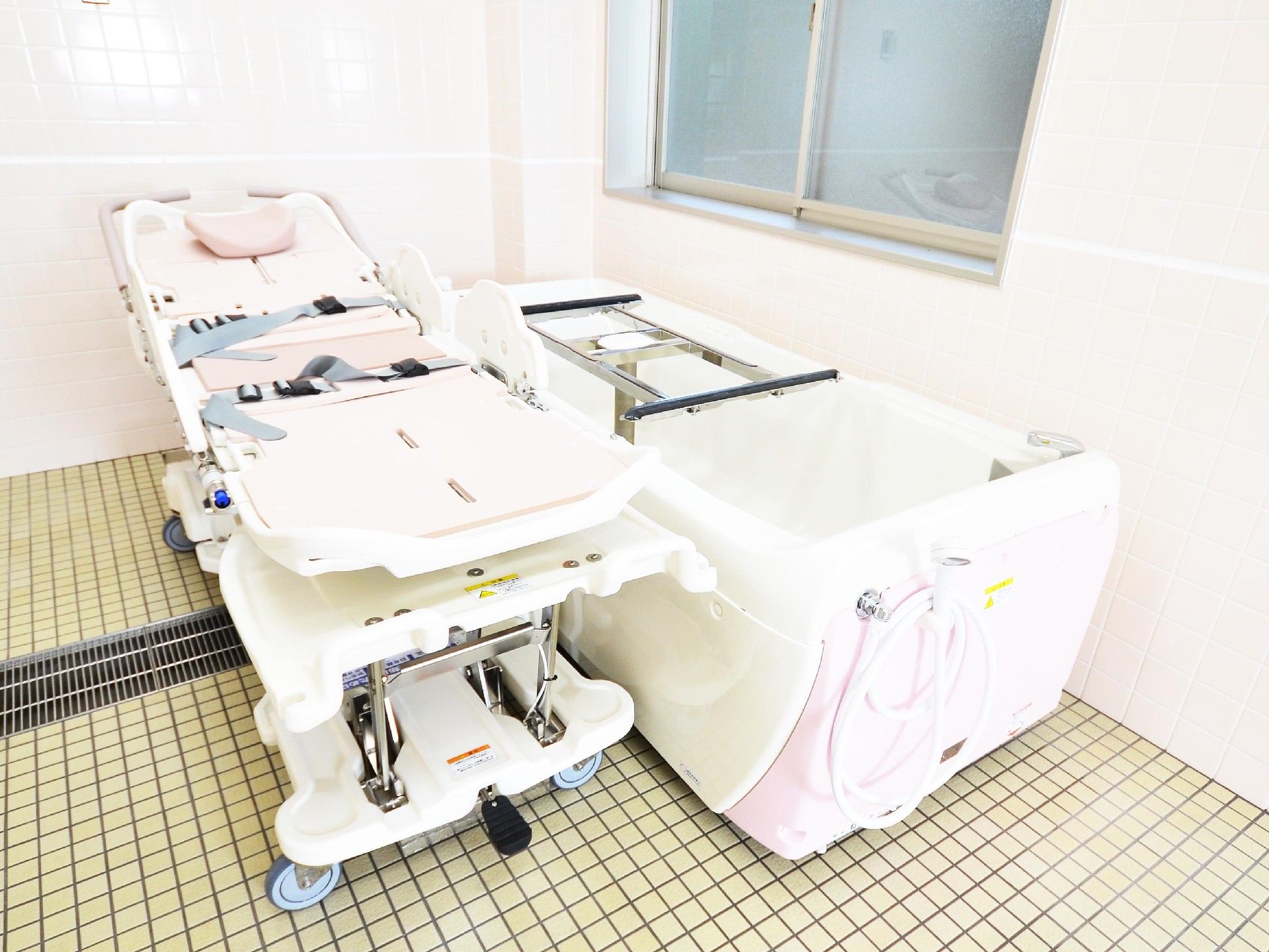 ピンクのタイルの浴室である。浴室の中には、介助が必要な方でもゆったりと入浴できる機械浴槽が設置されている。