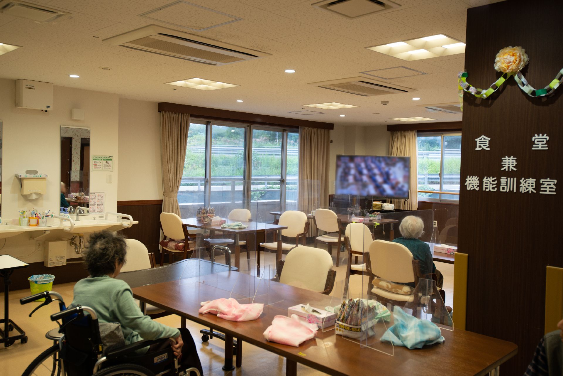 たくさんのテーブルと椅子が並べられている食堂兼機能訓練室