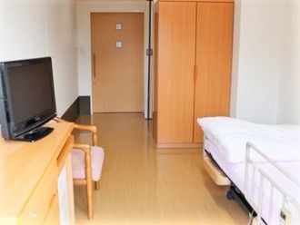 収納付きの広い部屋には介護用ベッドやテレビ、いすもある。