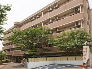 横に長い５階建ての建物。各フロアにベランダが付き、庭もある。