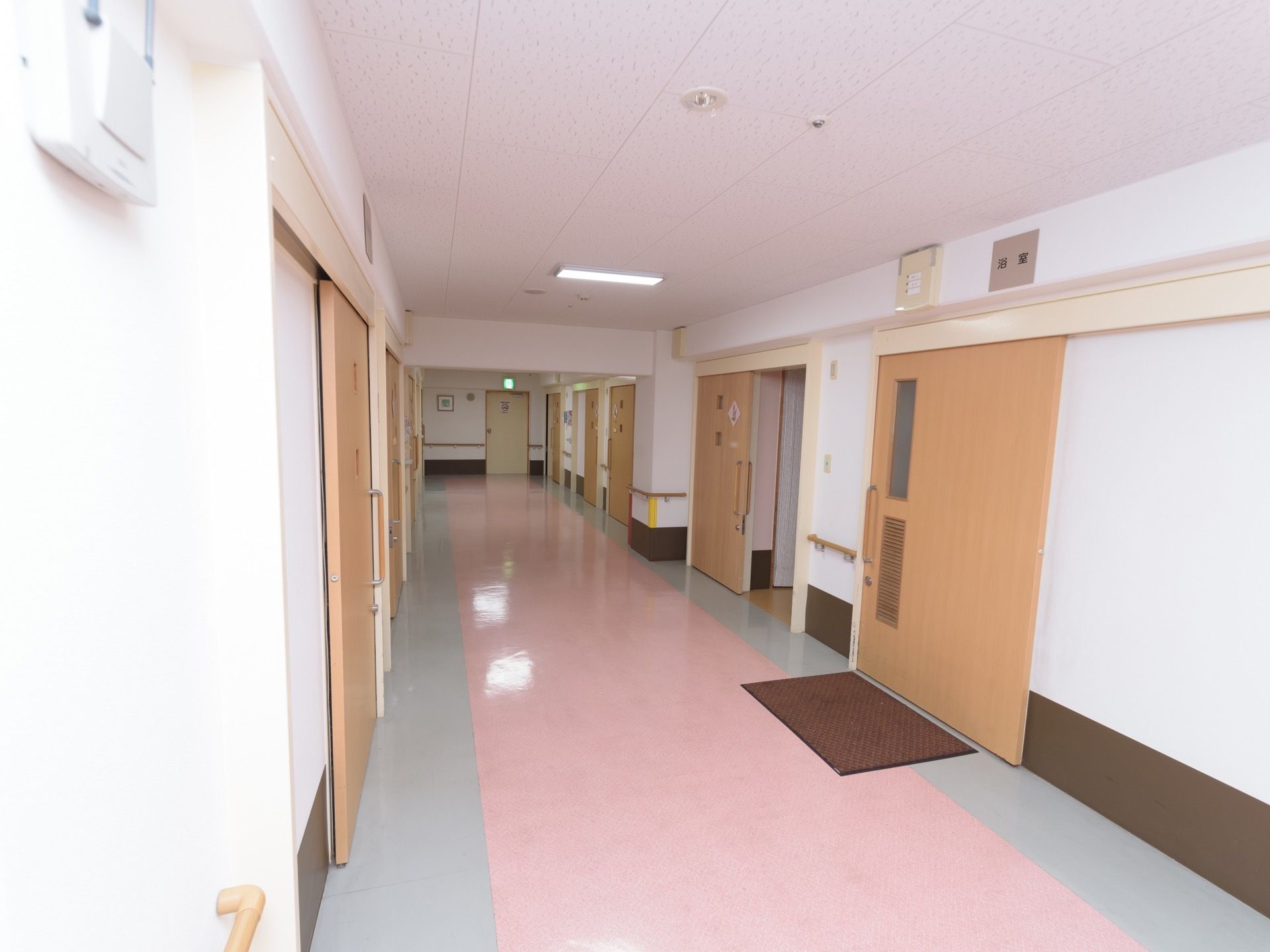 通路の床は、パステル系のピンクとグレーのツートンカラーである。各部屋のドアはスライド式を採用している。