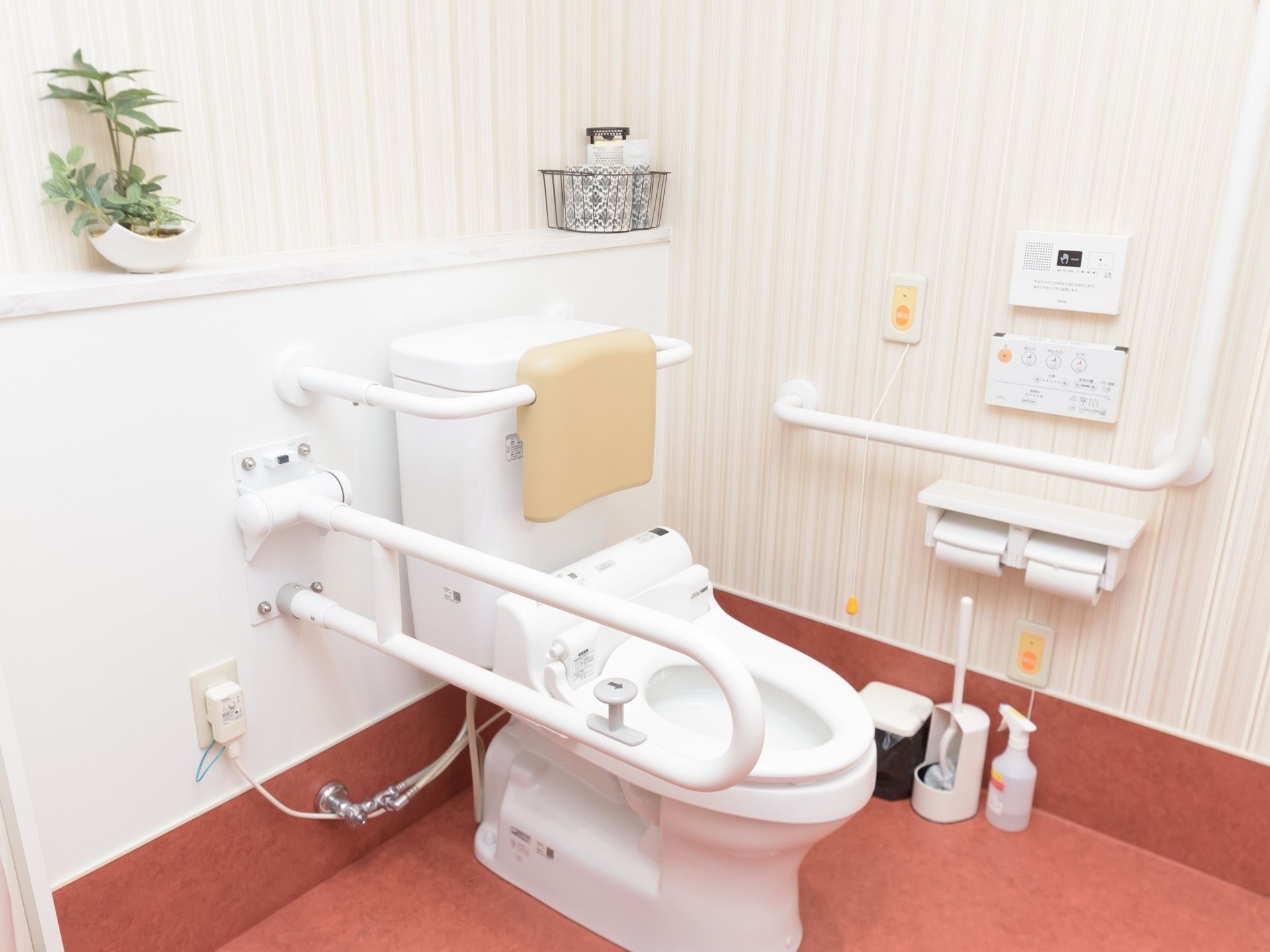 トイレには温水洗浄便座が設置されており、背もたれや可動式の手すりが備えてある。便器の後ろには棚が設けられており、観葉植物などが置かれている。