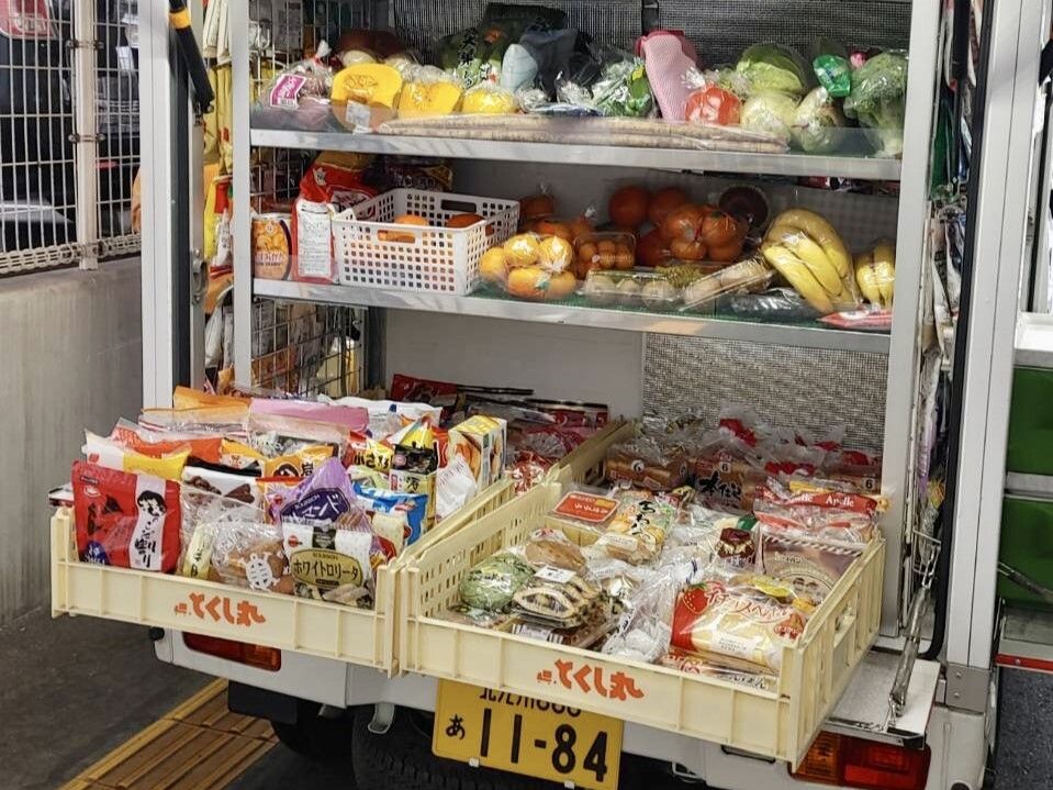 様々な食品が詰められたトラック内の様子。棚が3段あり、上の2段には野菜や果物、一番下には菓子などがある。
