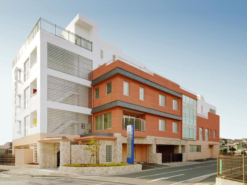 白とブラウンの4階建ての建物のある敷地内には駐車場があり、日当たりも良好。