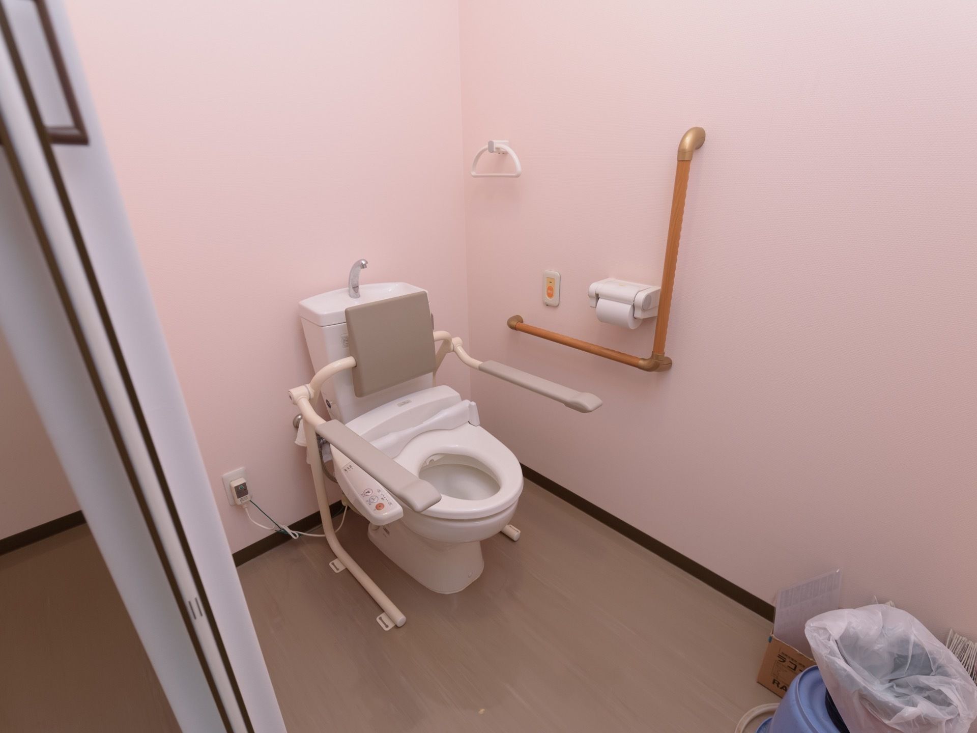 トイレには手洗い管の付いた温水洗浄便座が設置。壁にはＬ型の手すりやトイレットペーパーホルダー、タオル掛けなどが取り付けられている。