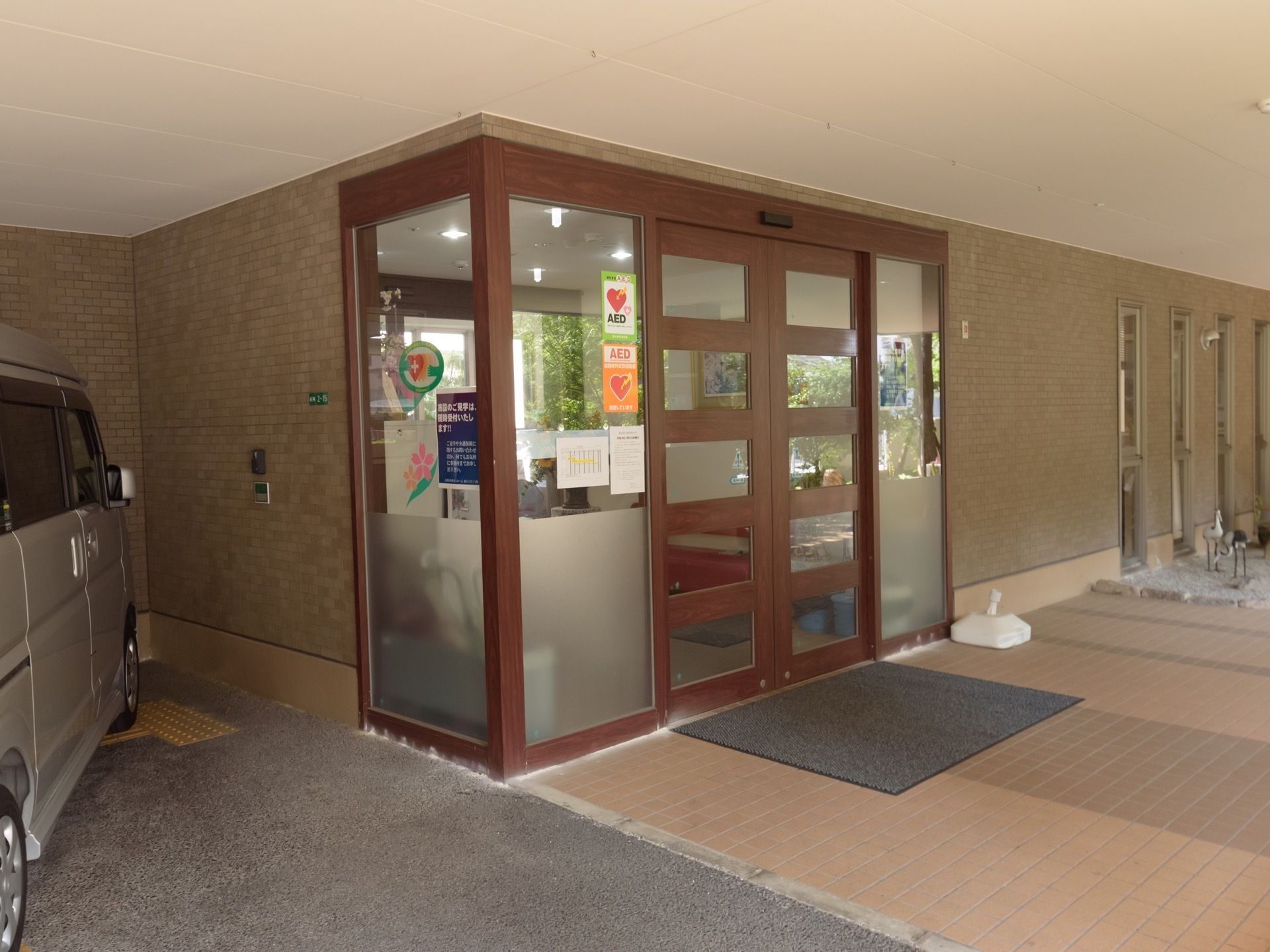 玄関扉は自動ドアが採用されており、横にあるガラスにはAEDを設置していることを示すステッカーが貼られている。