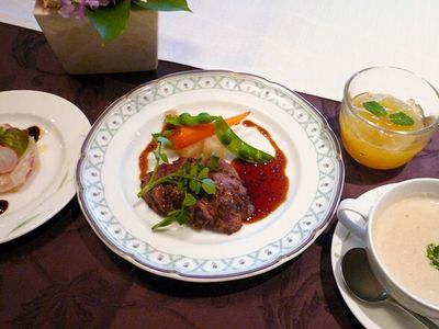 赤ワインソースがかかった肉のソテーをメインとした洋風のコース料理。ポタージュや前菜、フルーツゼリーなどが並んでいる。