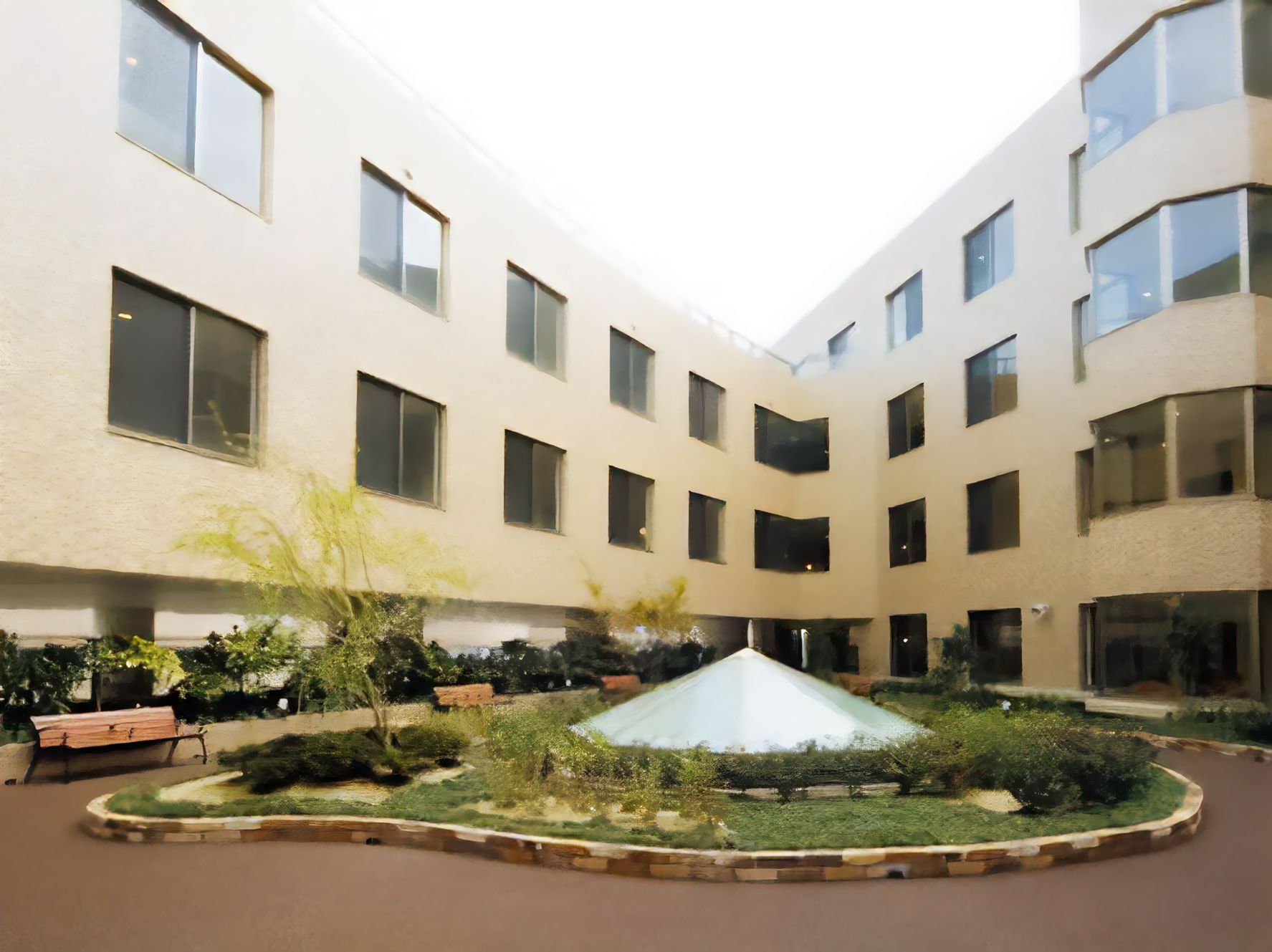 ベージュのどっしりとした大きな建物の前には手入れの行き届いた庭があり、中庭を囲む遊歩道にはベンチも複数置かれている。