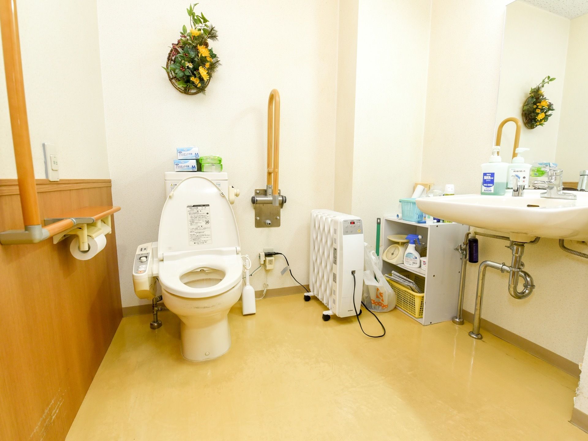 広々とした個室のトイレには、オイルヒーターを置いている。鏡、洗面台、出し入れ可能な手すりが設置されている。