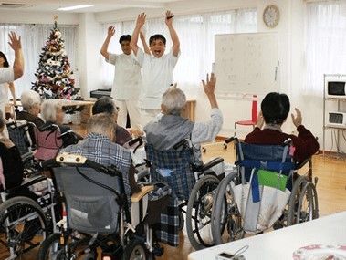 スタッフが手を挙げて合図し、それに従って同じ動作をしている高齢者の様子