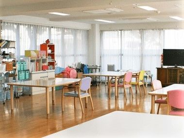 二面採光の明るいリビングスペースの様子。カラフルな調度品や家庭的なサイズのテーブルがある