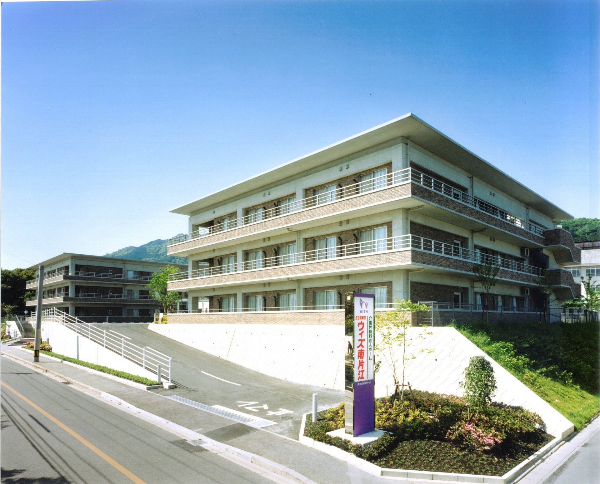 茶色い建物に各階にベランダがある
