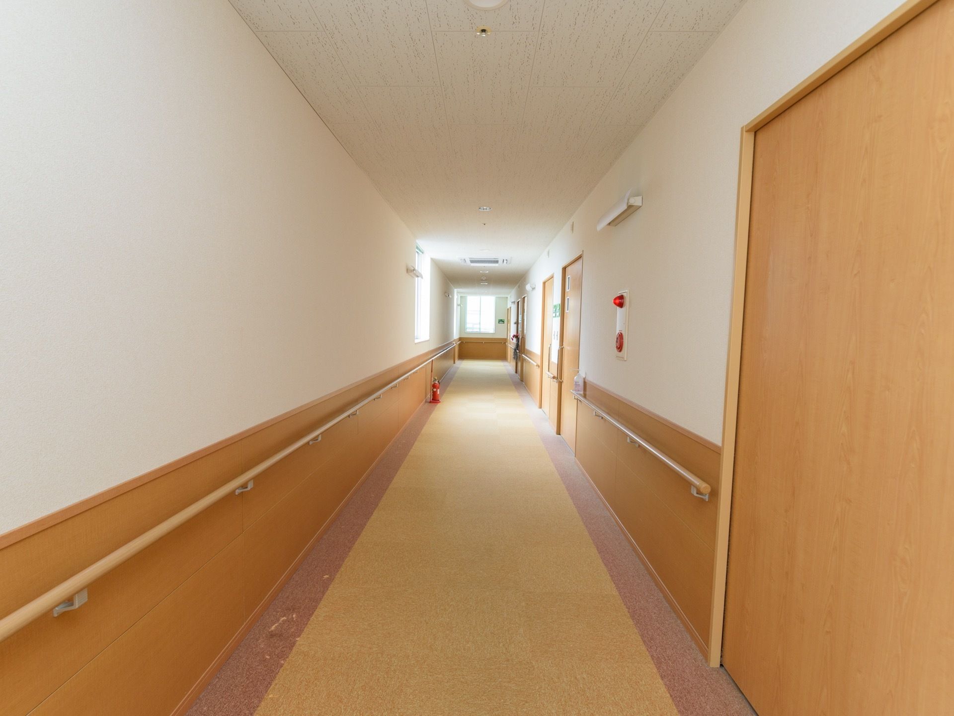 突当たりまでまっすぐに伸びる廊下は、窓から陽光が差し込んで明るい。居室のドアは引き戸になっており、通行を妨げる心配がない。