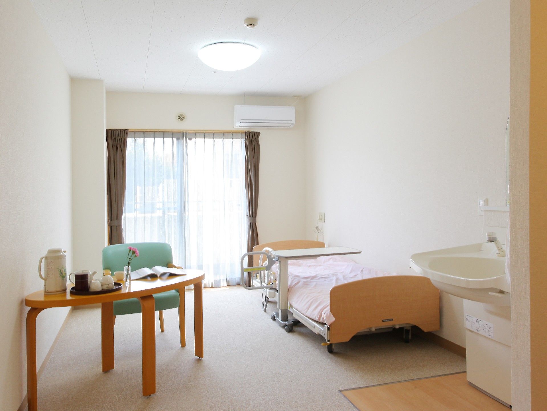 ベランダの広い窓から明るい陽光が入る、居心地の良い個室である。入居者様が持参された家具を入れても十分な広さがあり、快適にお過ごしいただける。