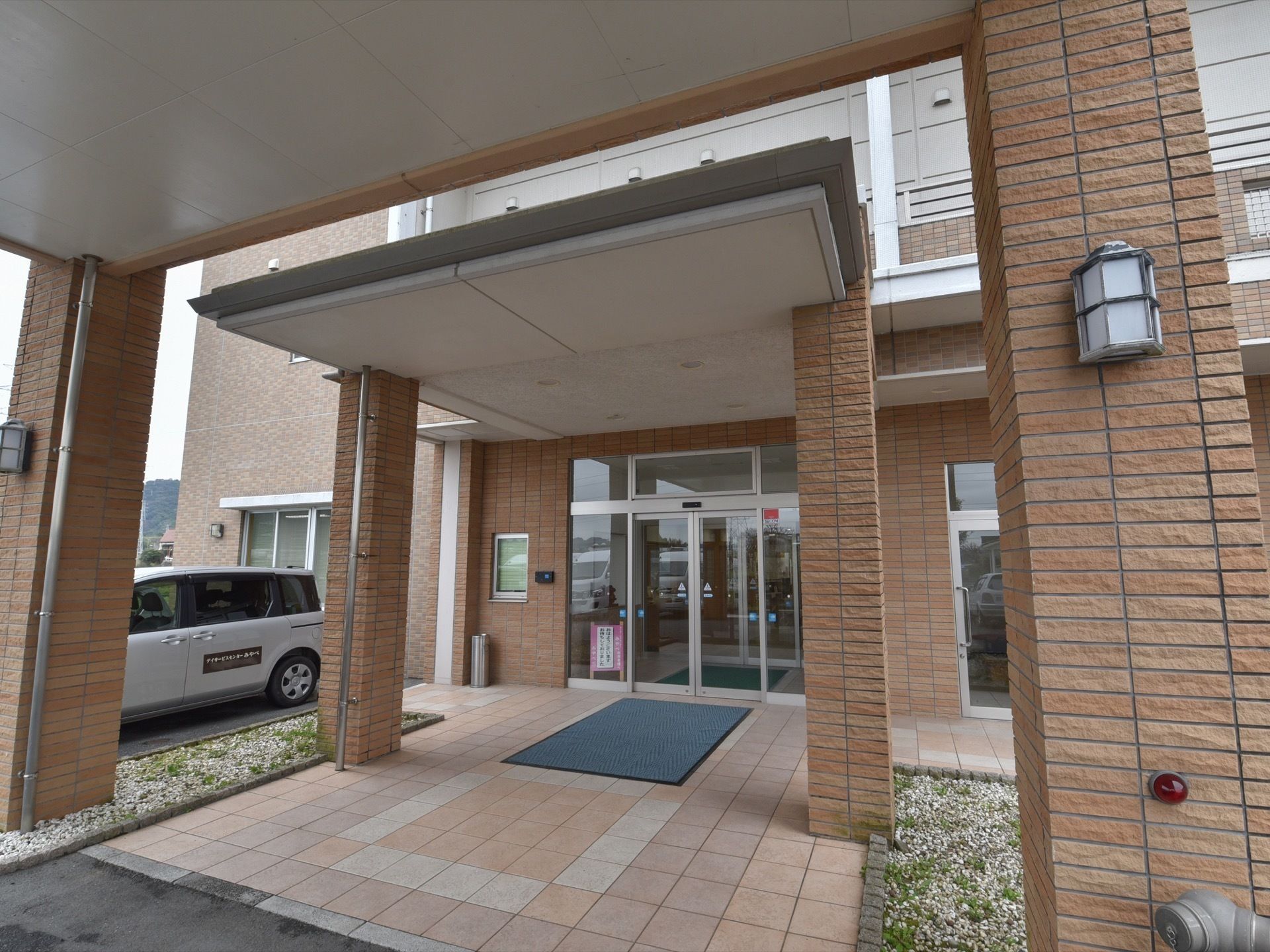 建物入口前のスペースはとても広くタイルが敷かれていて、大きな屋根が付いている。入口はガラスの自動ドアになっている。