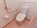 フローリングの床の上に温水洗浄便座が付いた洋式トイレが設置されている。壁にはＬ字の手すりとナースコールが付いている。