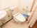 カーテンで仕切られた洋式トイレと洗面台がある。壁にはＬ字型の手すりと、ナースコールがある。