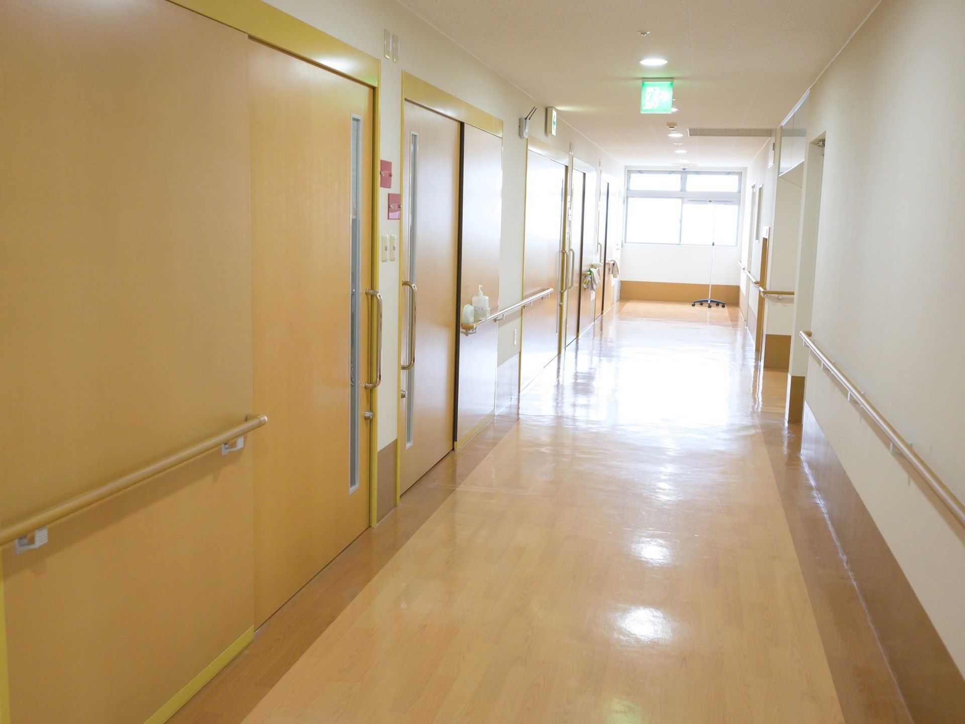 通路には居室の扉が並んでいる。直線であり、突き当りに腰高窓がある。床はベージュ色のビニール素材である。