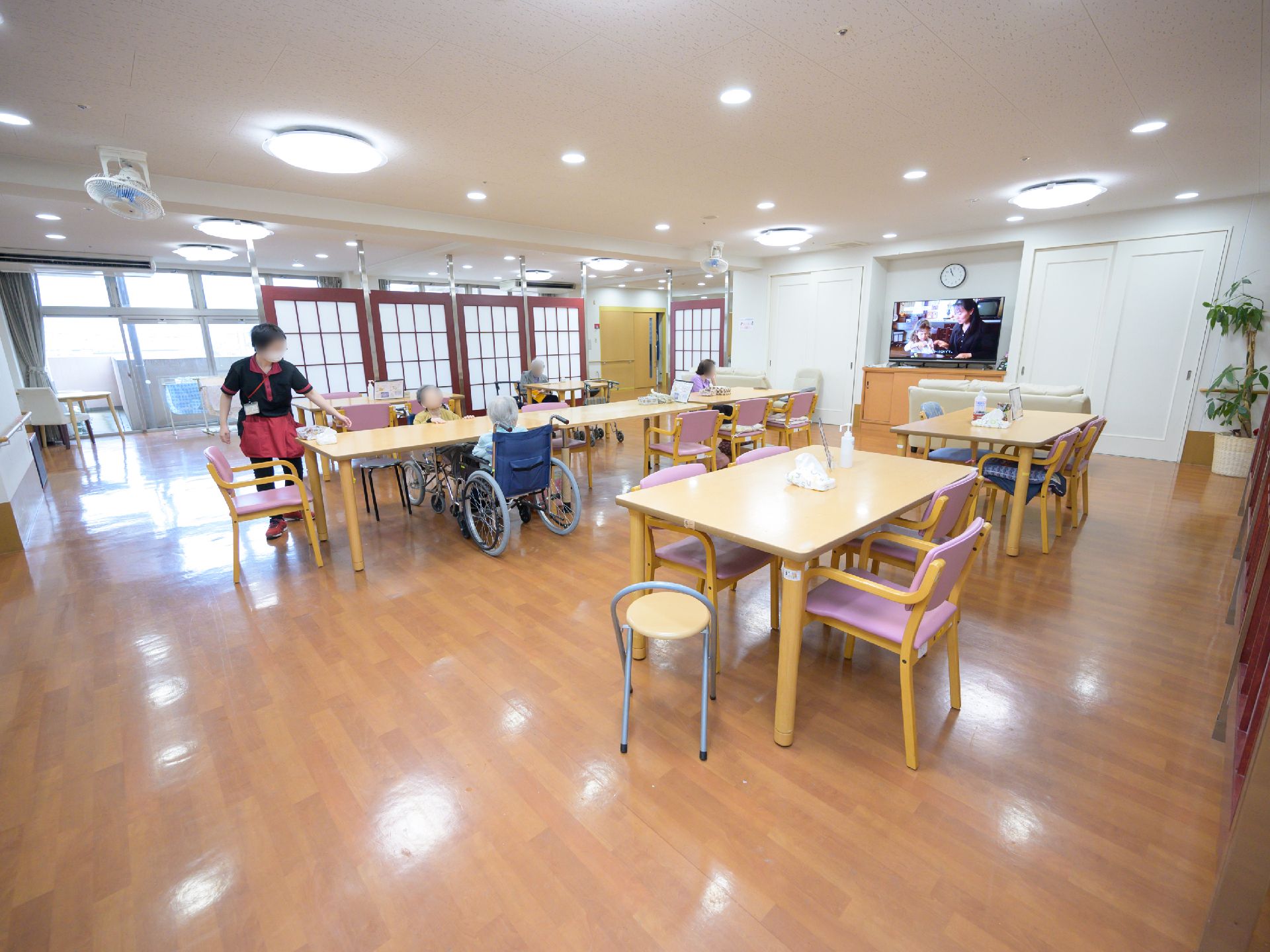 テーブルやイスが並んだダイニングルームで、入居者様たちが思い思いに過ごす様子