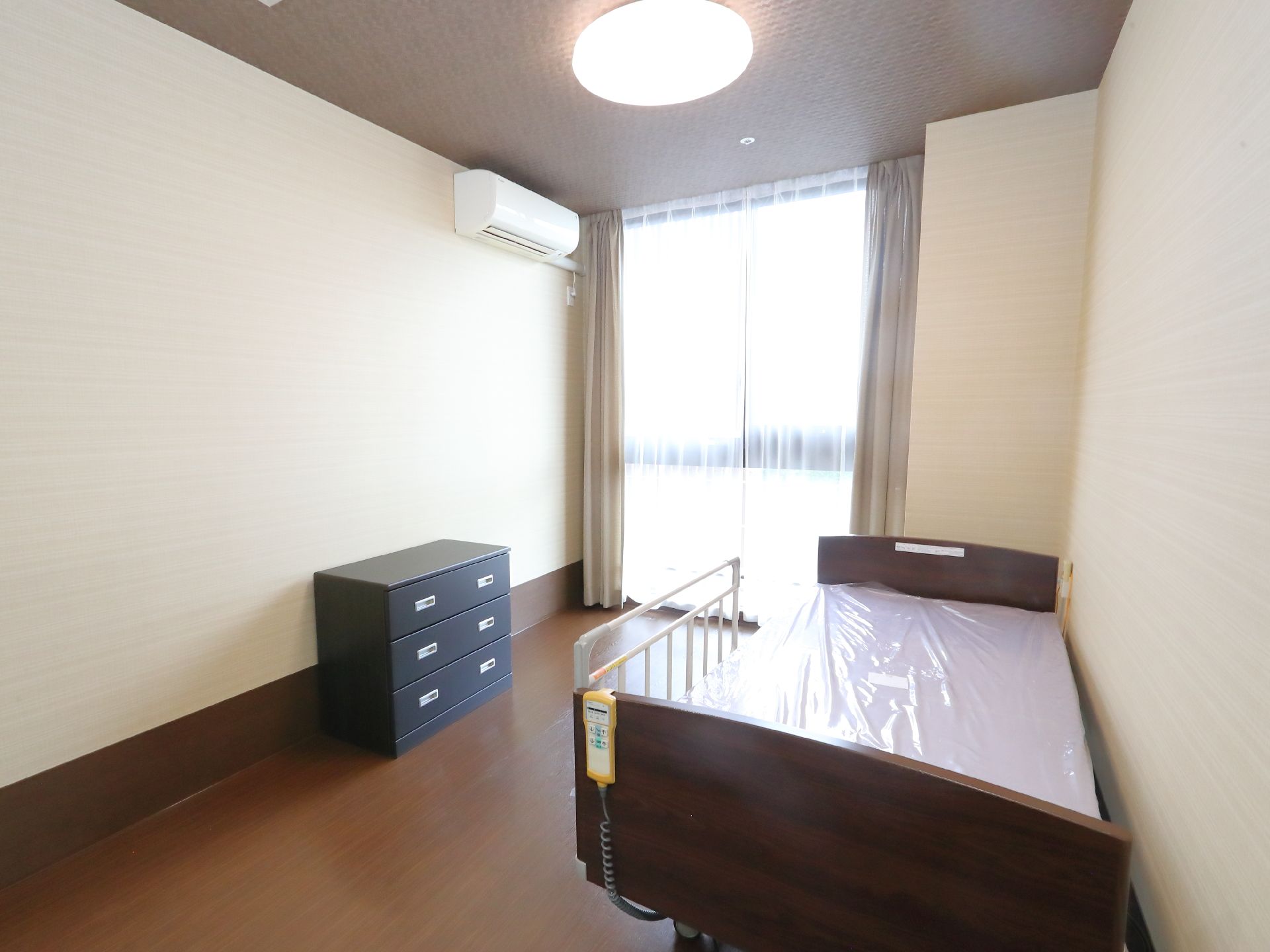 日の光が差し込むベッドが置かれた白い壁の部屋