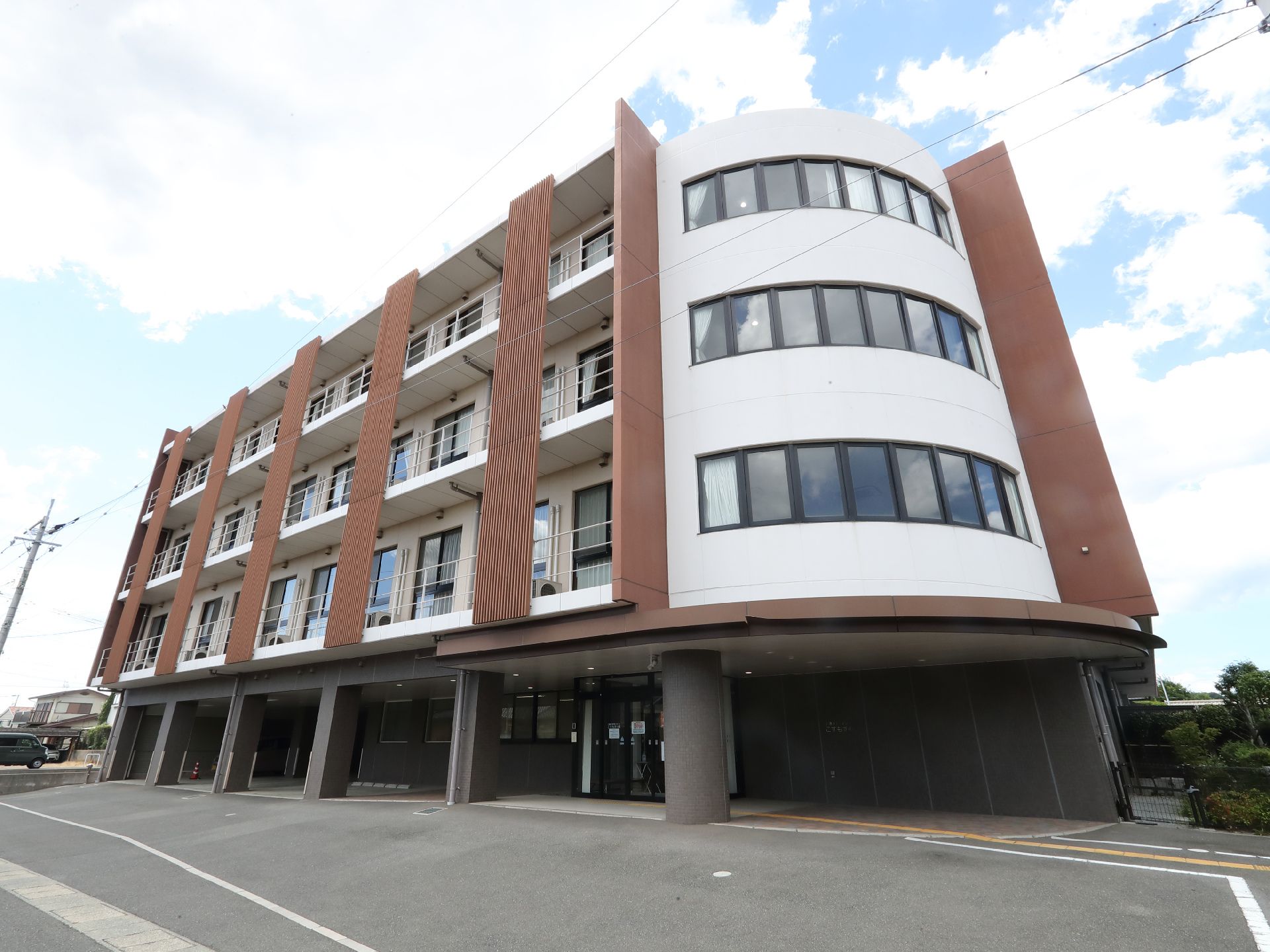 アスファルトに隣接している白と茶色の外観で４階建ての建物