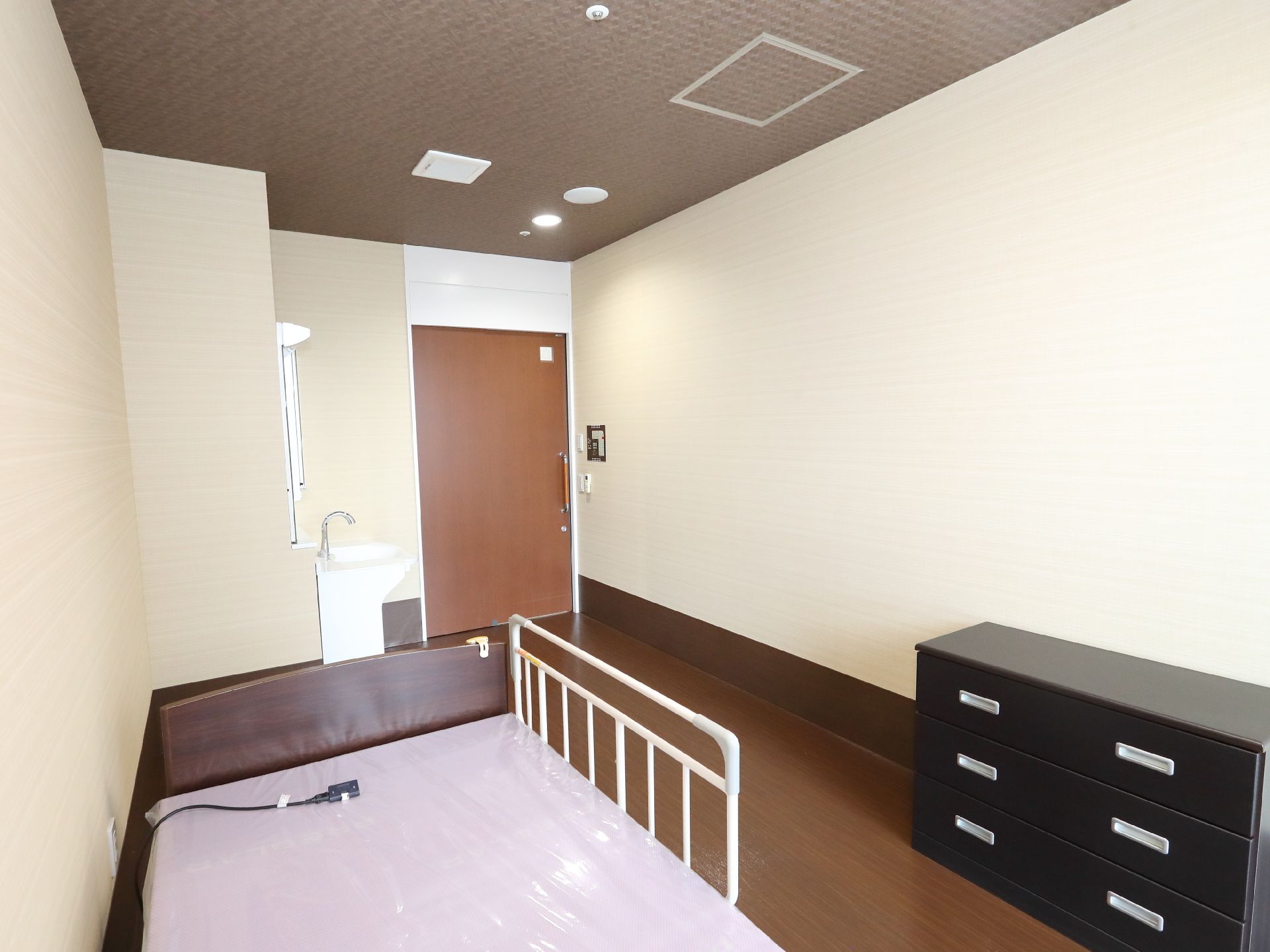 ベッドと黒い棚が置かれた白い壁の部屋