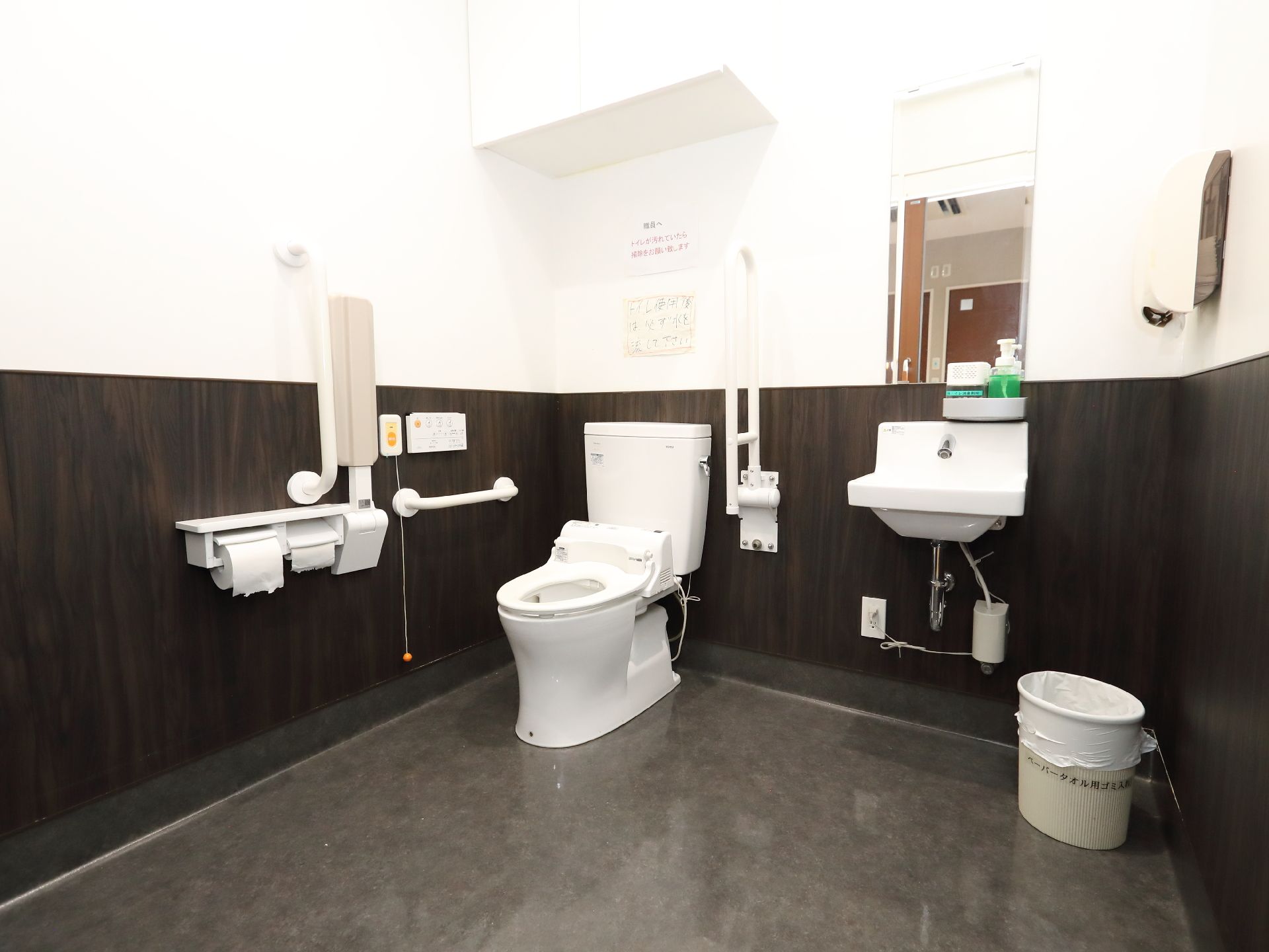 黒と白の壁の部屋に置かれた洗面台と洋式便器